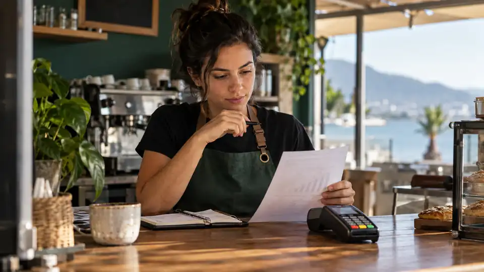 Empreendedora analisando custos de vendas ao lado de uma maquininha